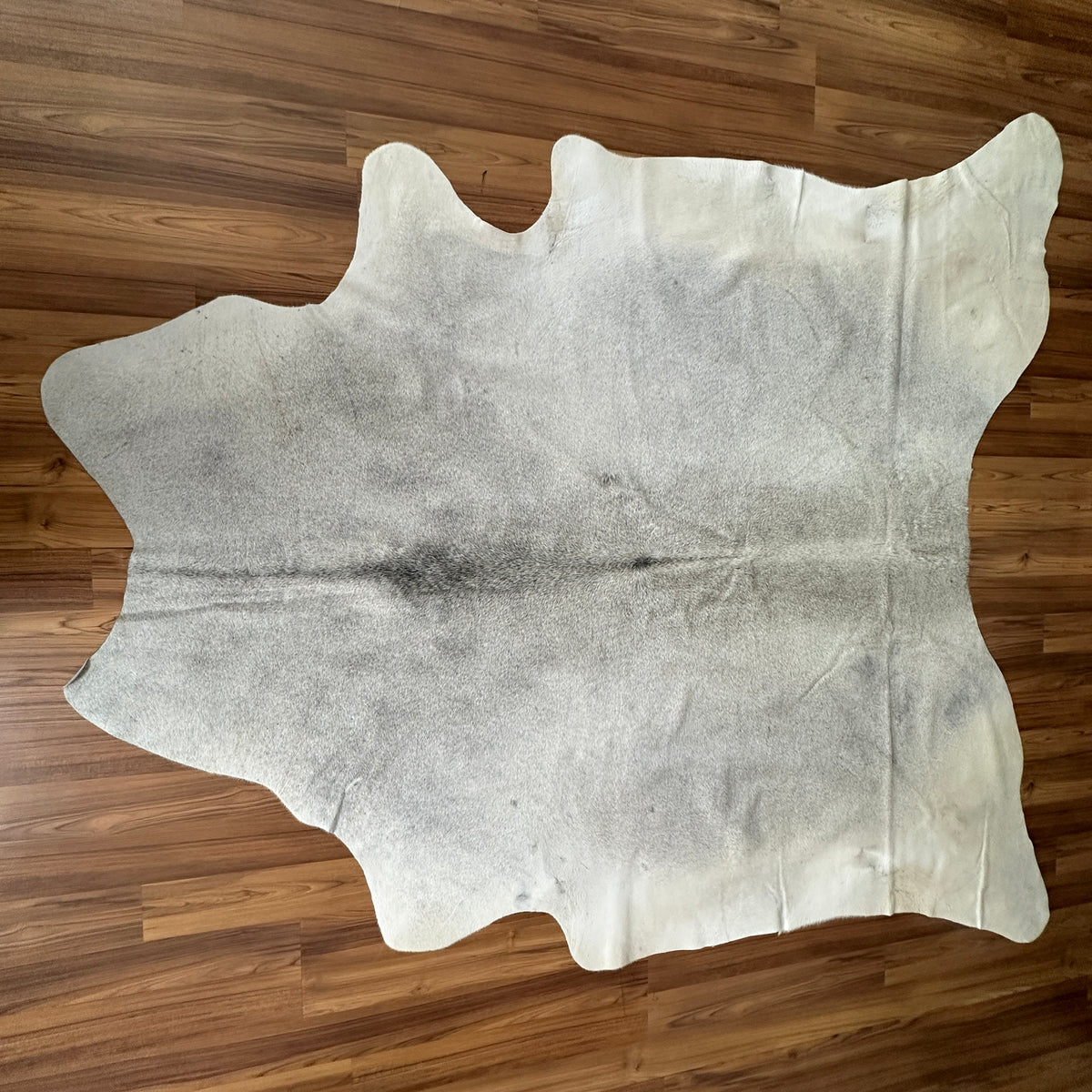 Beige cowhide rug, full overhead view — Large irregular cream and grey patches with subtle charcoal markings