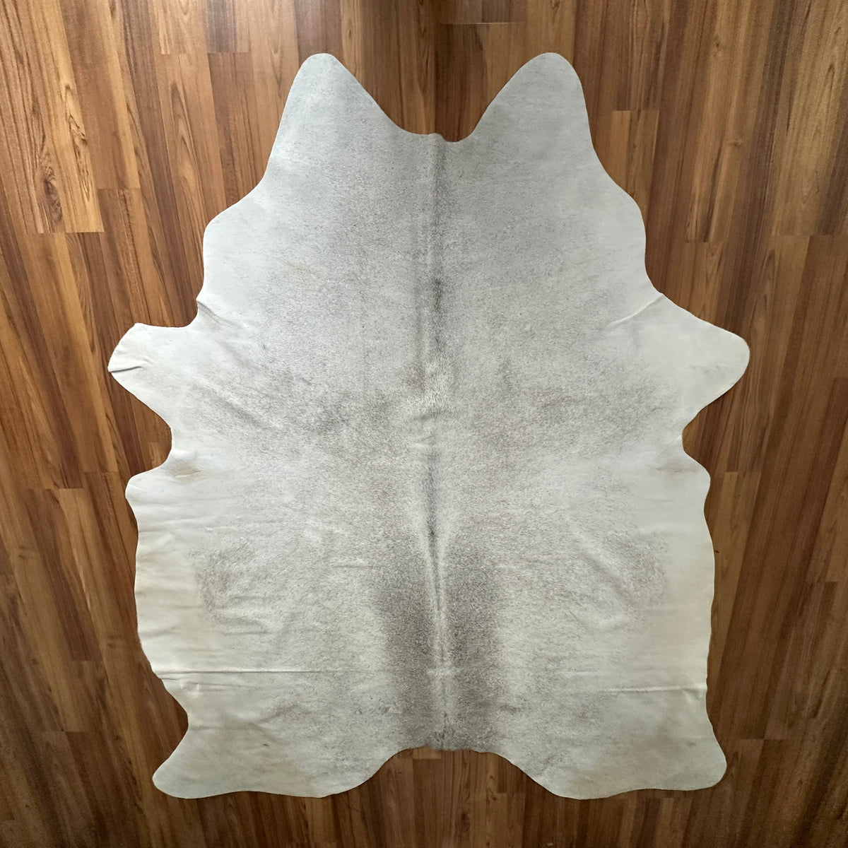 Beige cowhide rug, full overhead view — Light cream base with subtle gray-brown natural markings and irregular patches