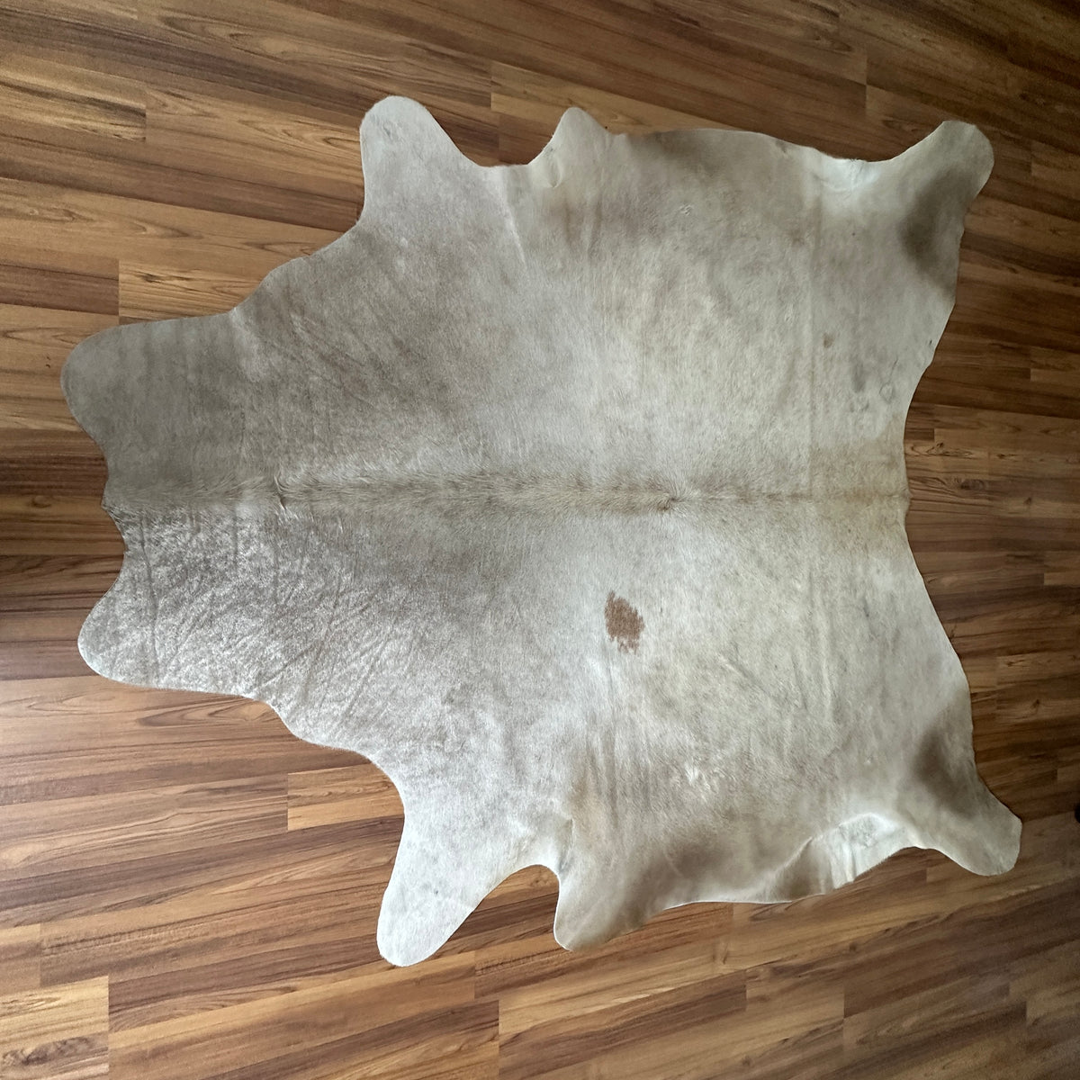 Beige cowhide rug, full overhead view — Large irregular cream patches with fine brown speckle and mottled texture throughout