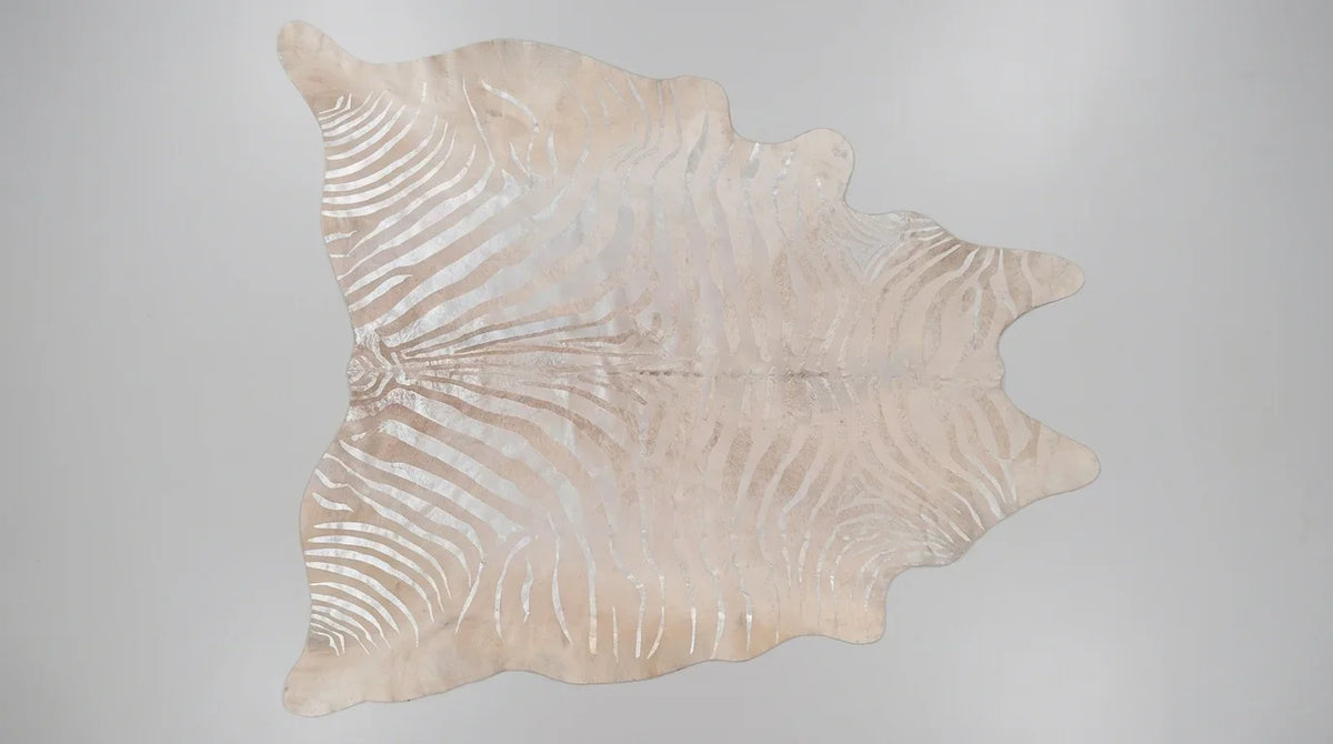 Beige cowhide rug flat lay on white background showing full hide shape