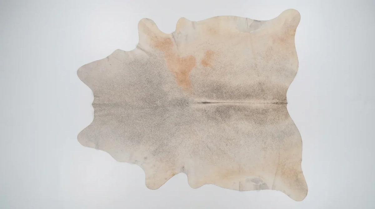 Beige cowhide rug flat lay on white background showing full hide shape