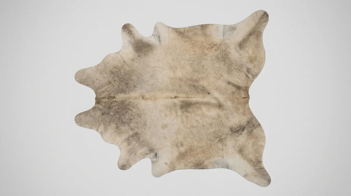 Beige cowhide rug flat lay on white background showing full hide shape