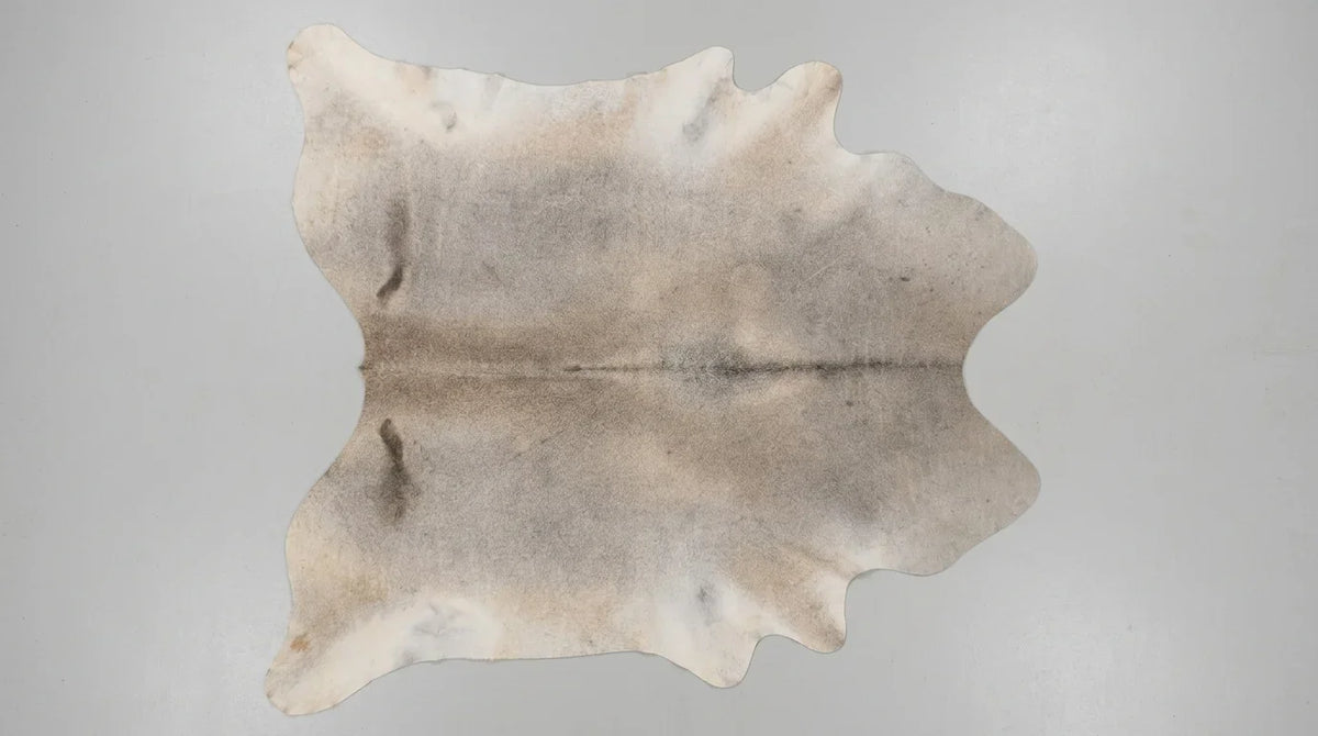 Beige cowhide rug flat lay on white background showing full hide shape