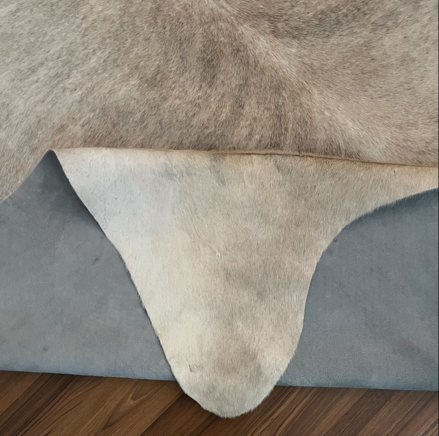 Close-up texture of Beige cowhide rug — Large irregular grey-brown patches over cream base with natural hide markings