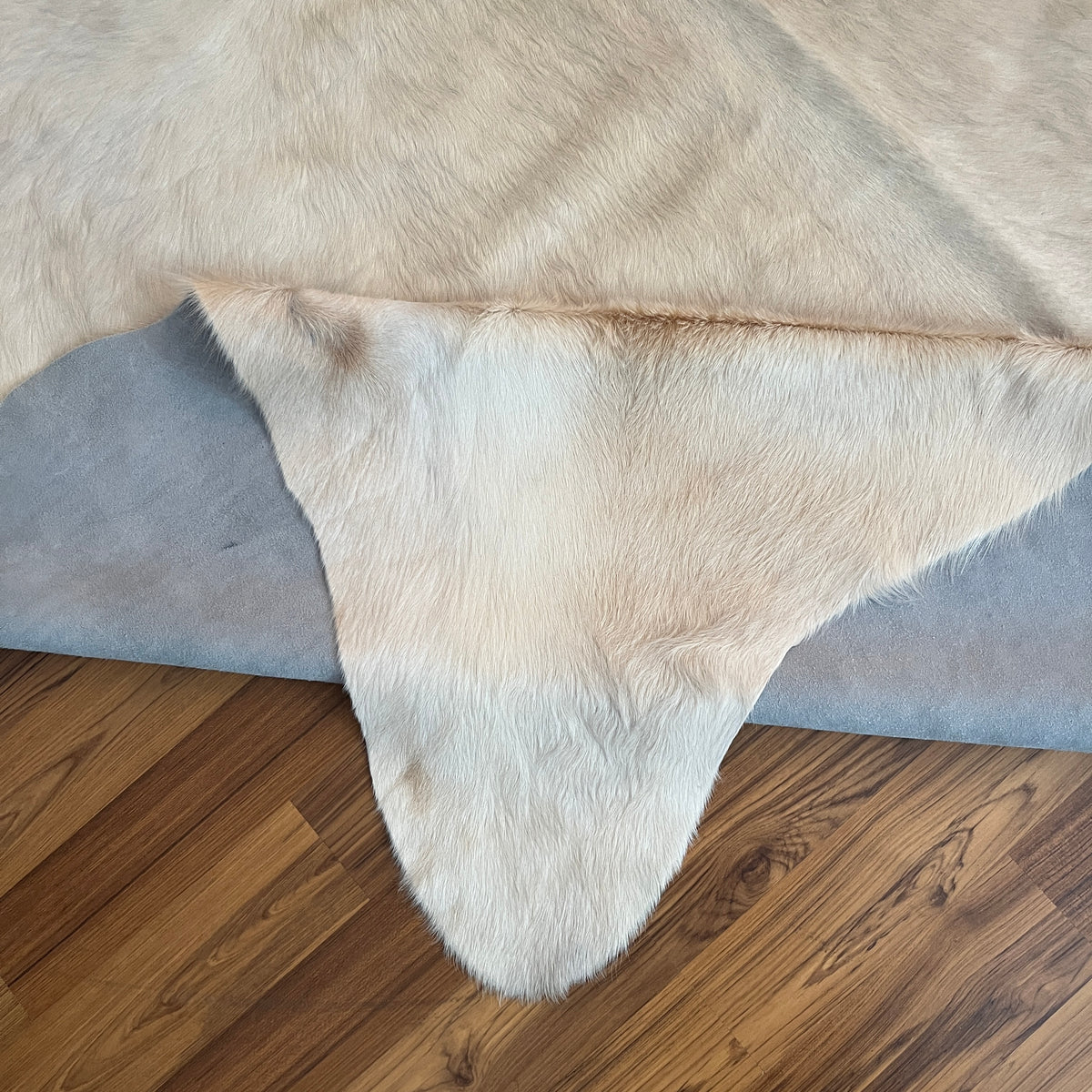 Close-up texture of Beige cowhide rug — Subtle cream and off-white natural markings over pale ivory base