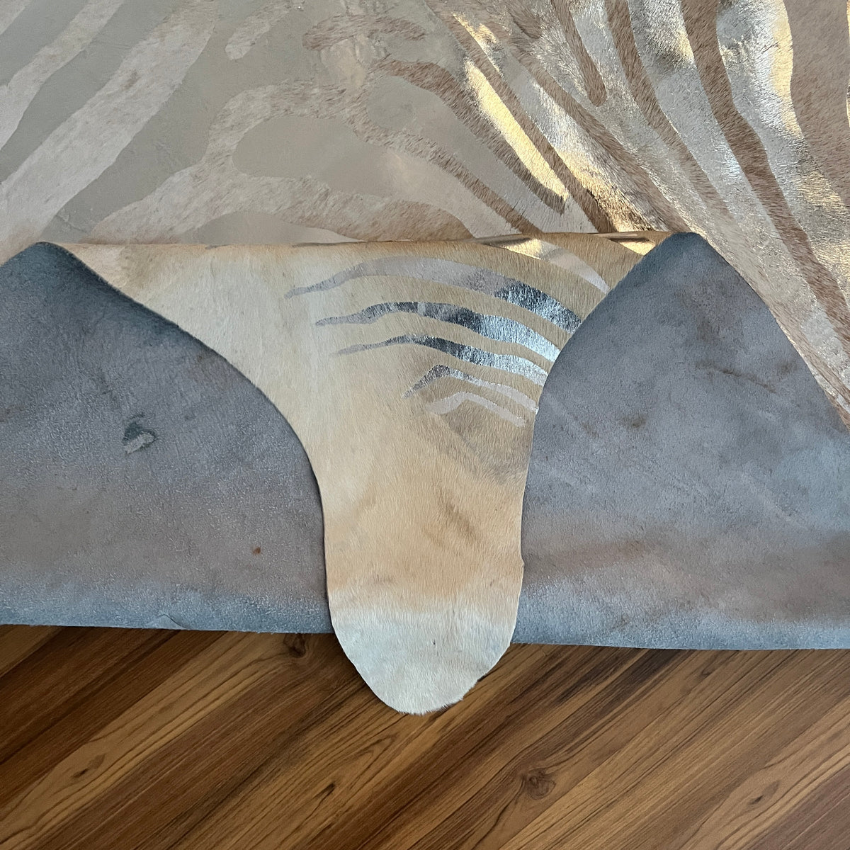 Close-up texture of Beige exotic cowhide rug — Fine zebra-striped metallic print in silver and cream over cream base