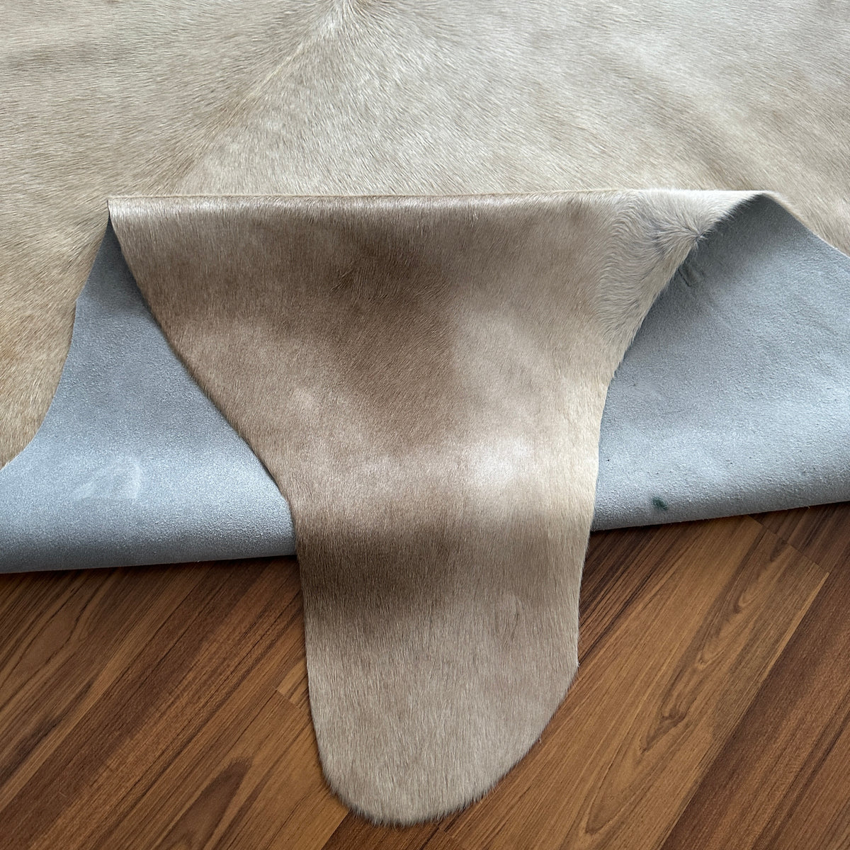 Close-up texture of Beige cowhide rug — Large irregular cream patches with fine brown speckle and mottled texture throughout