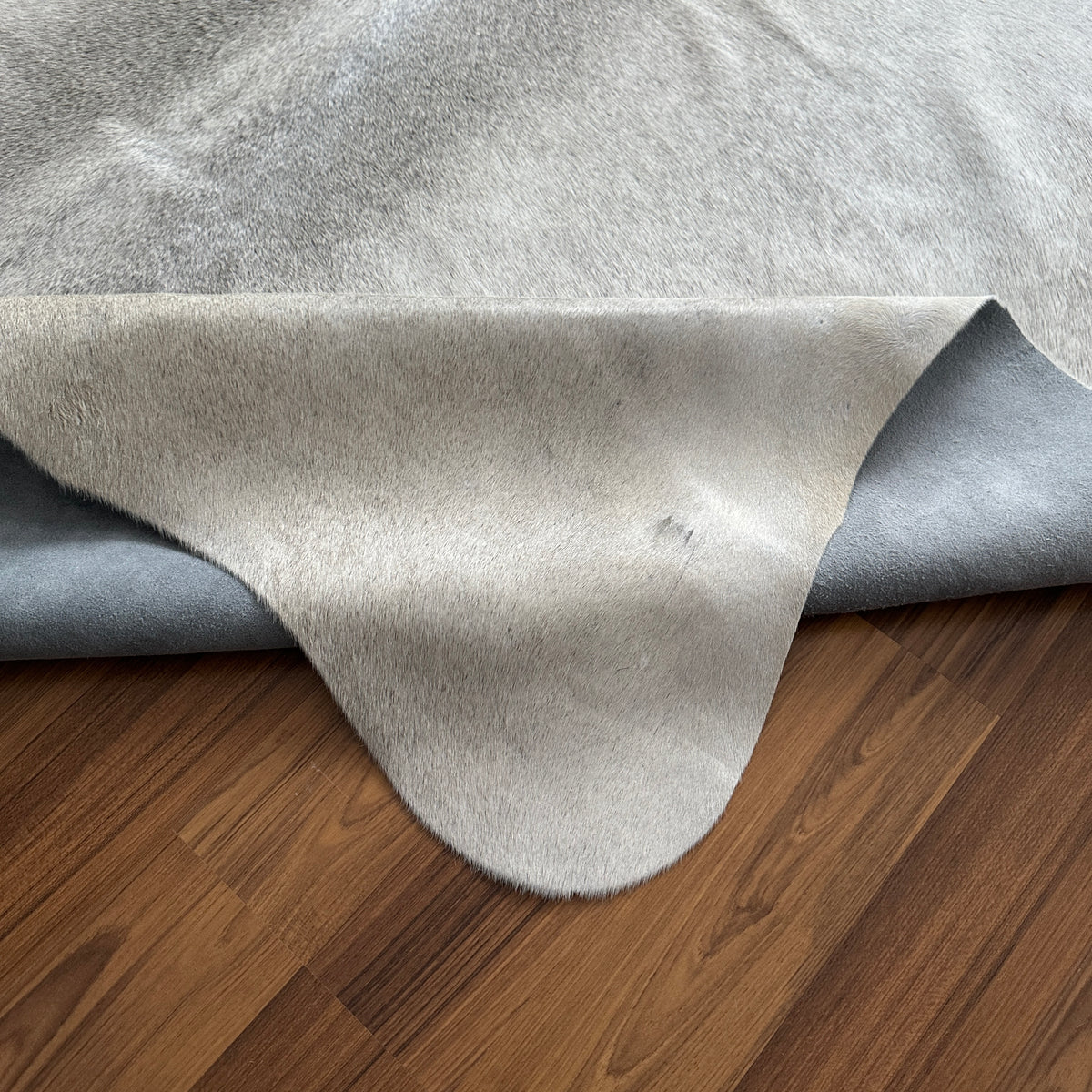 Close-up texture of Beige cowhide rug — Light cream base with subtle grey-brown natural markings and irregular patches