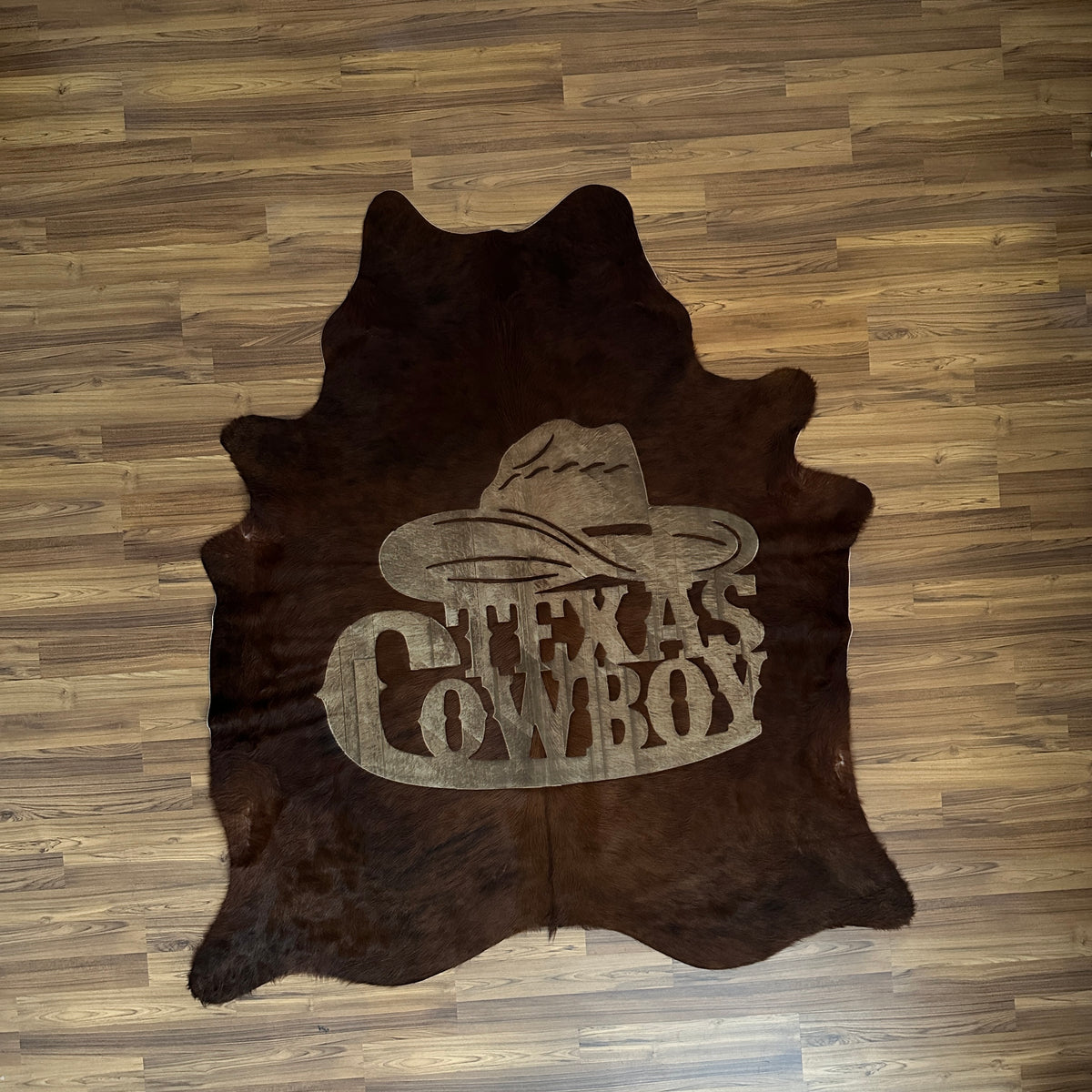 Black and White exotic cowhide rug, full overhead view — Large embossed cowboy boot and hat motif on dark brown-black base wi