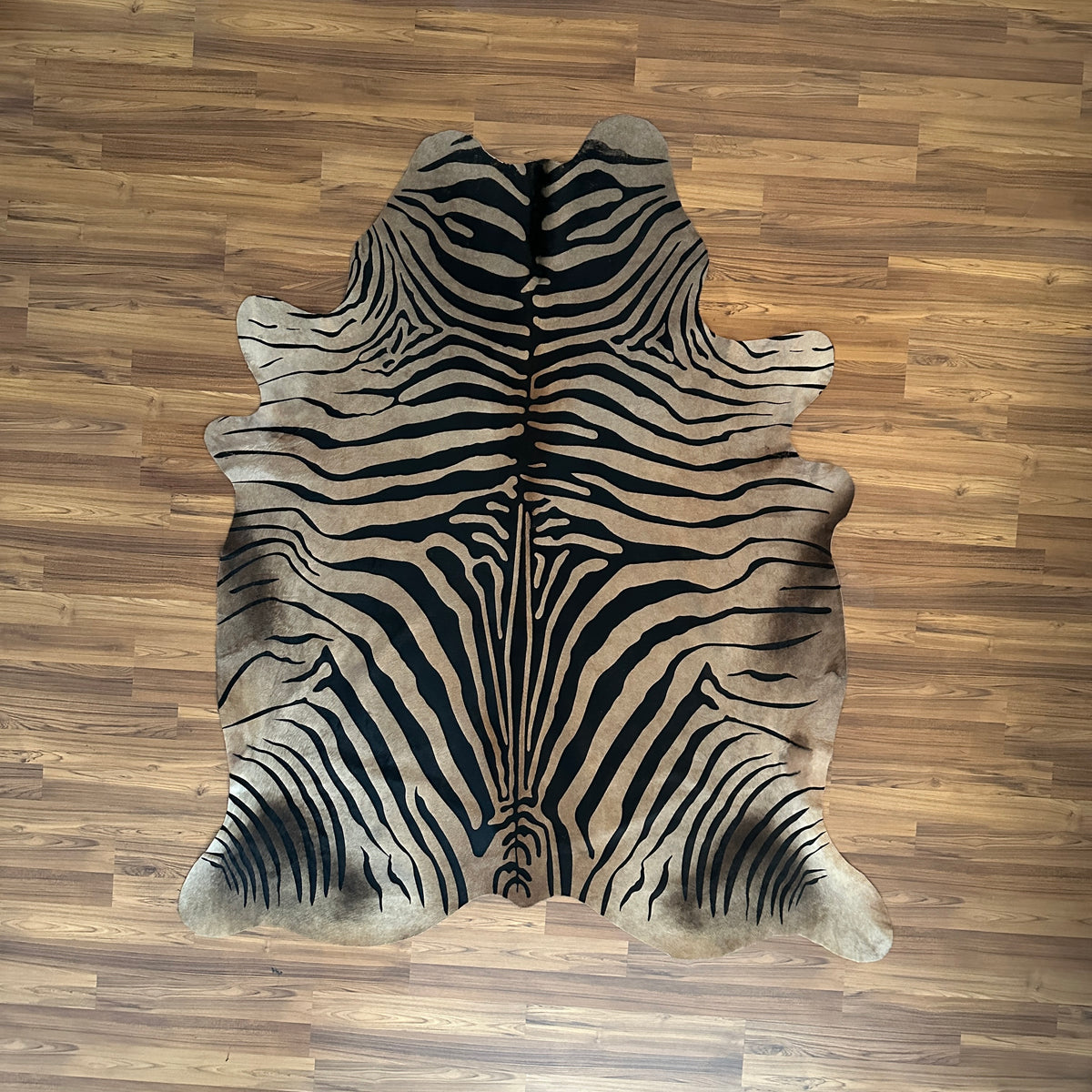 Black and White zebra print cowhide rug, full overhead view — Bold black stripes radiating symmetrically from center over cre