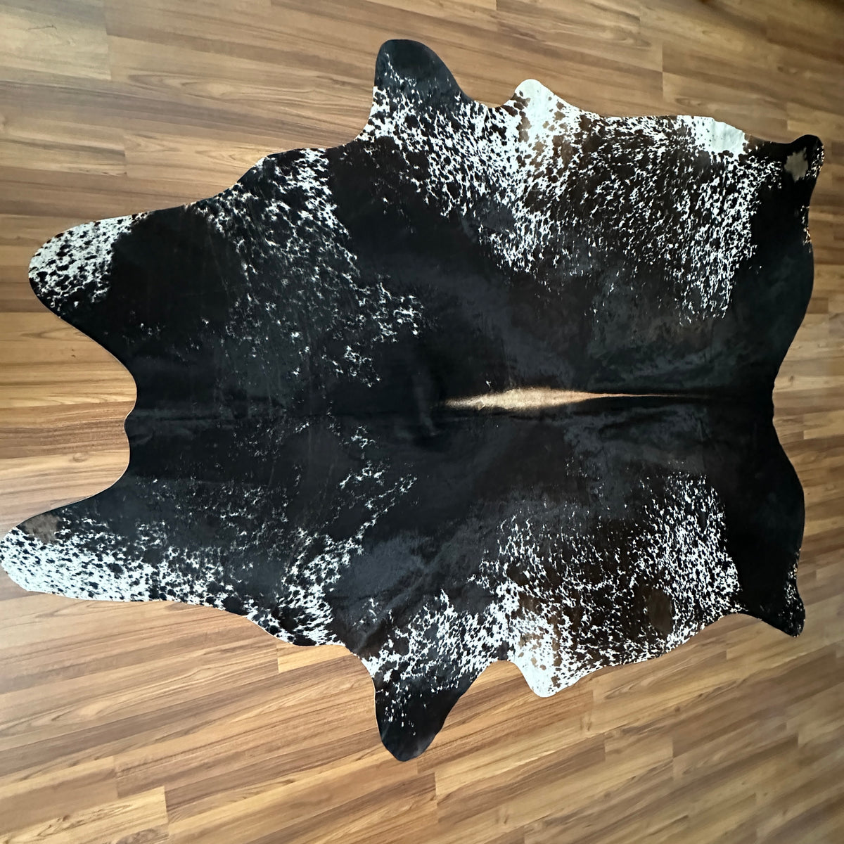 Black and White cowhide rug, full overhead view — Large irregular white speckles and patches over deep black base