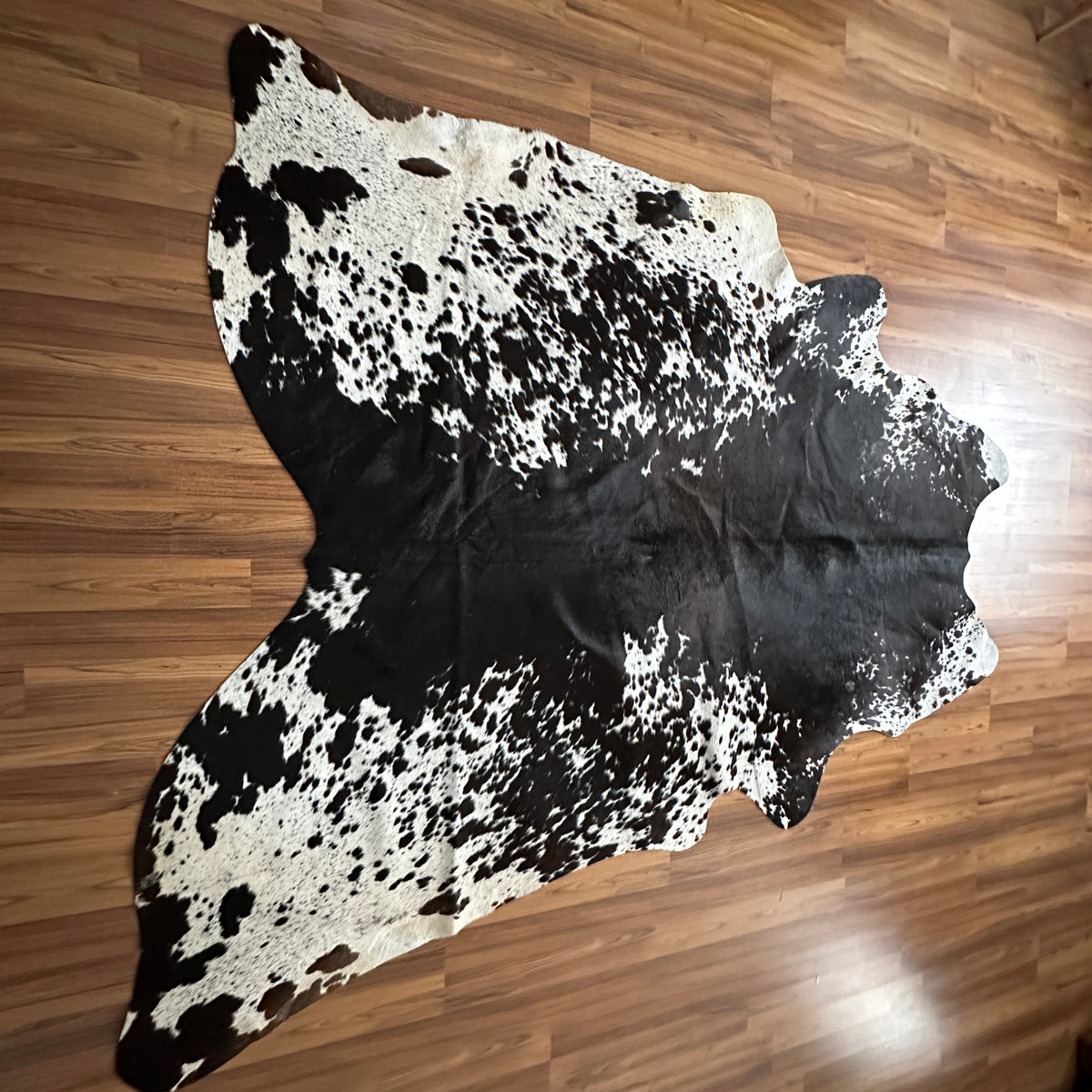 Black and White cowhide rug, full overhead view — Large irregular black patches and speckles over white base with natural hid
