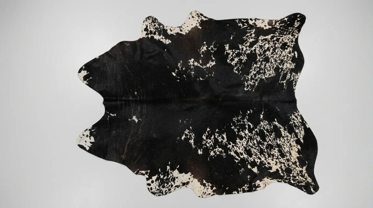 Black and White cowhide rug flat lay on white background showing full hide shape