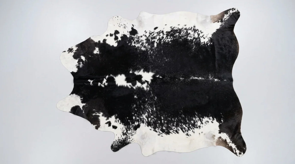 Black and White cowhide rug flat lay on white background showing full hide shape
