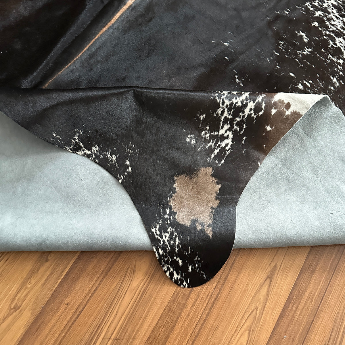 Close-up texture of Black and White cowhide rug — Large irregular white speckles and patches over deep black base