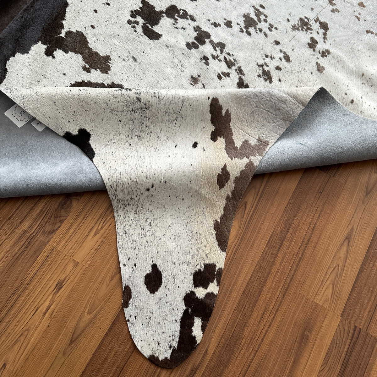 Close-up texture of Black and White cowhide rug — Large irregular dark brown patches with fine speckled overlay on cream base
