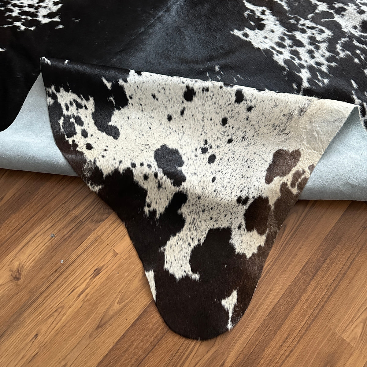 Close-up texture of Black and White cowhide rug — Large irregular black patches and speckles over white base with natural hid