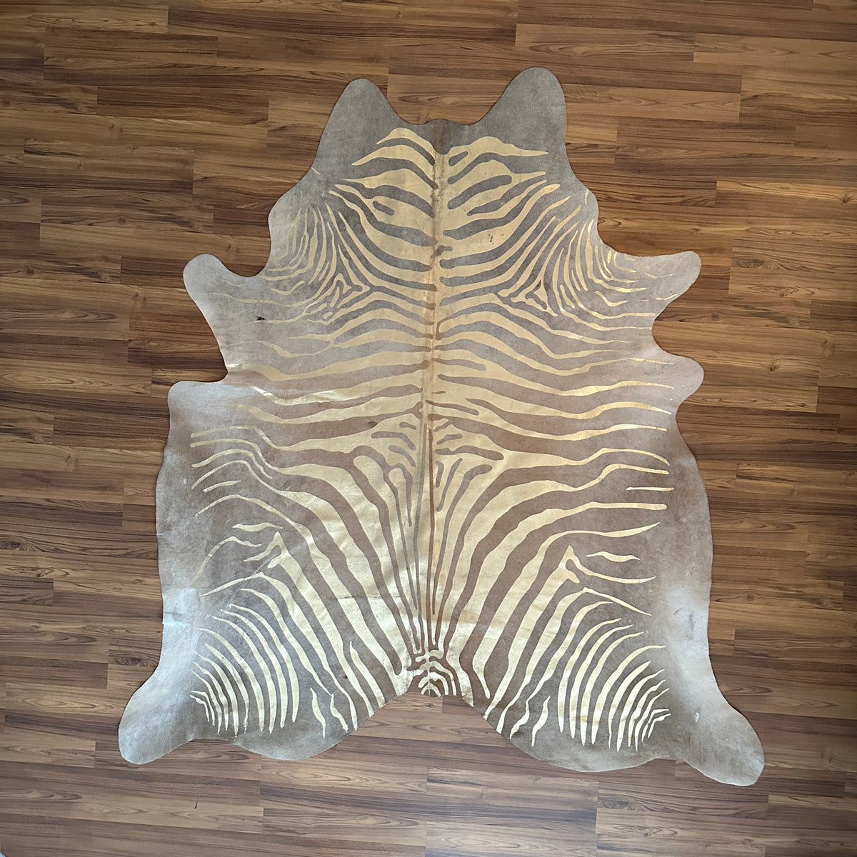 Brown and White zebra print cowhide rug, full overhead view — Bold zebra stripes radiating from center spine, cream and tan b