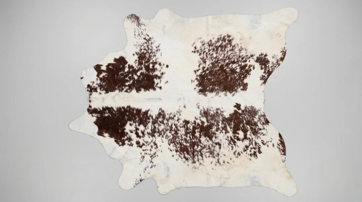 Brown and White cowhide rug flat lay on white background showing full hide shape