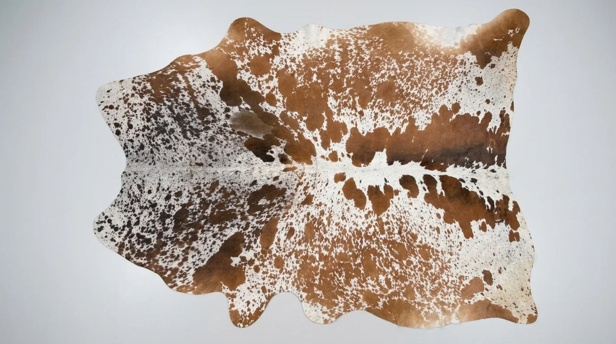 Brown and White cowhide rug flat lay on white background showing full hide shape