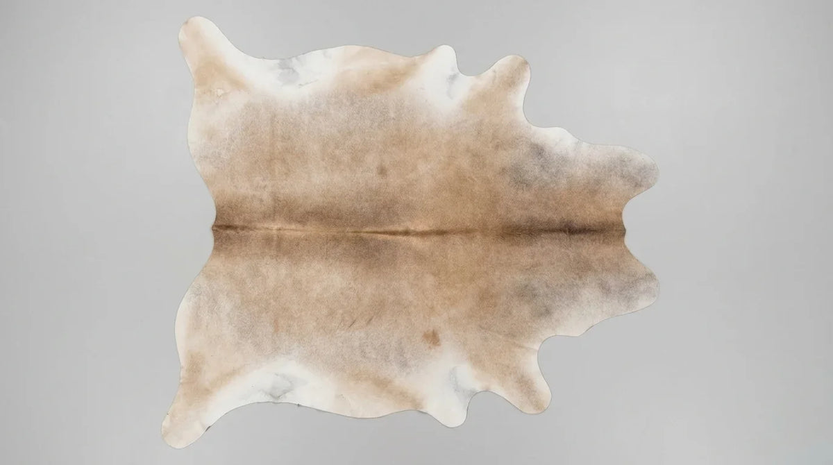 Brown and White cowhide rug flat lay on white background showing full hide shape