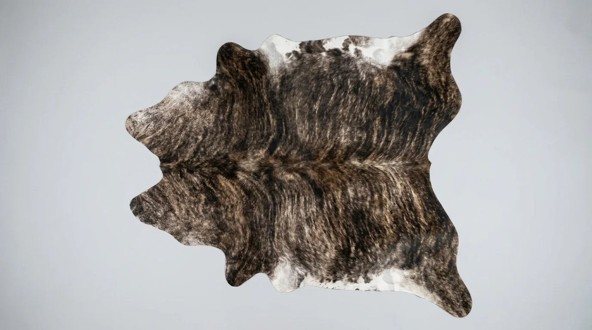 Brown and White cowhide rug flat lay on white background showing full hide shape