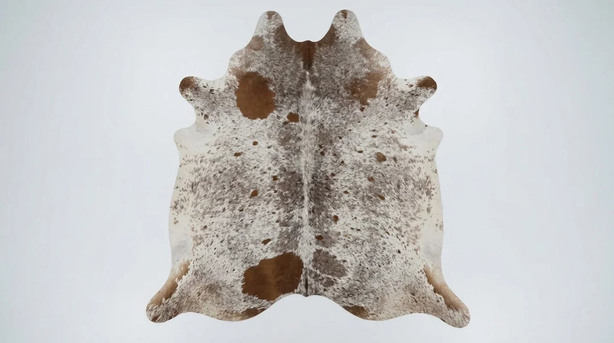 Brown and White cowhide rug flat lay on white background showing full hide shape