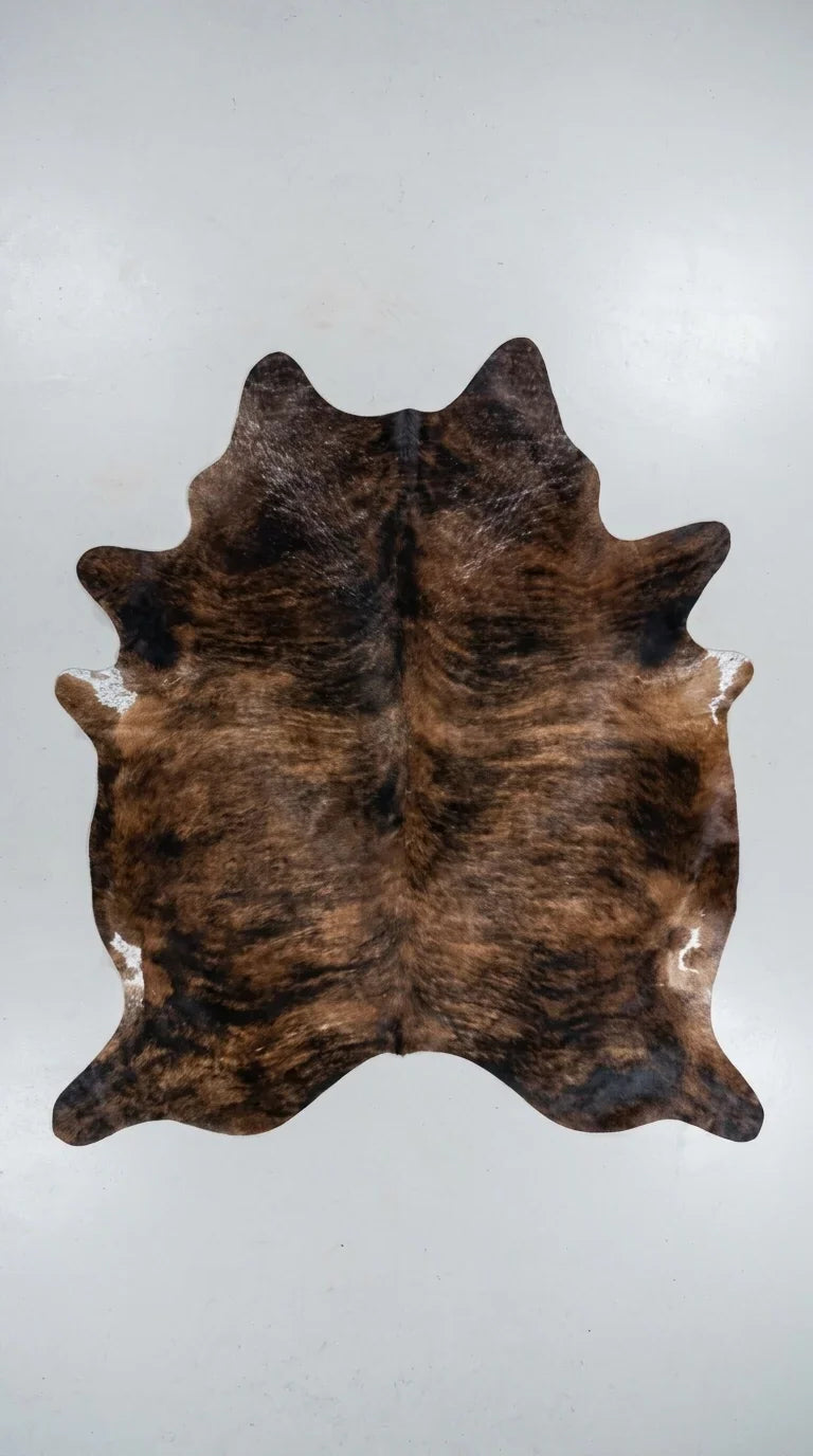 Brown and White cowhide rug flat lay on white background showing full hide shape