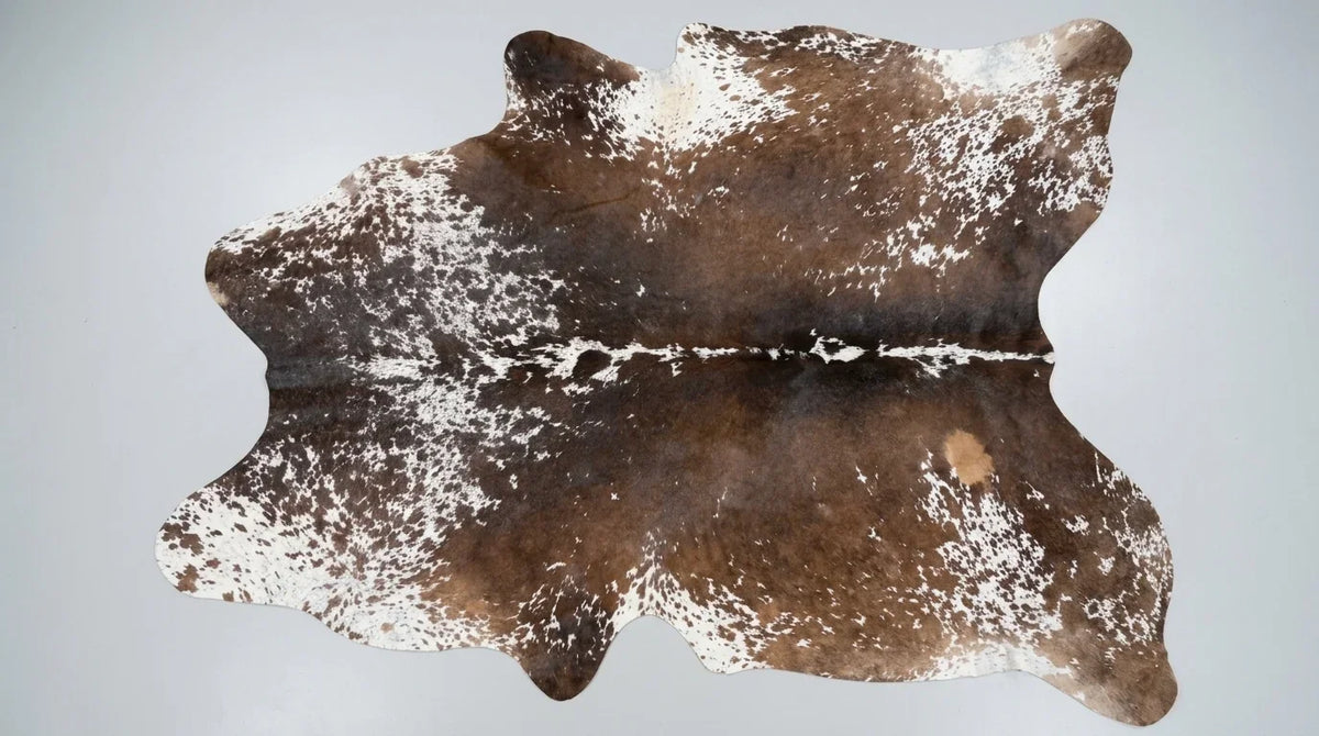 Brown and White cowhide rug flat lay on white background showing full hide shape