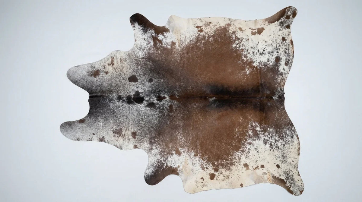 Brown and White cowhide rug flat lay on white background showing full hide shape