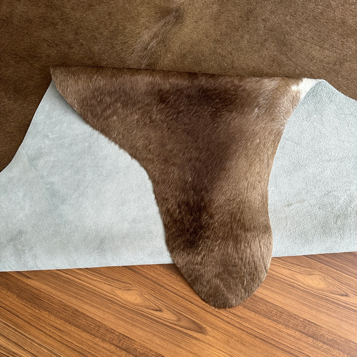 Close-up texture of Brown and White cowhide rug — Large irregular chocolate brown patches over cream and white base