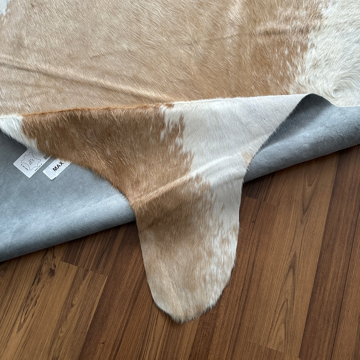 Close-up texture of Brown and White cowhide rug — Large irregular tan and brown patches with white accents and belly stripe
