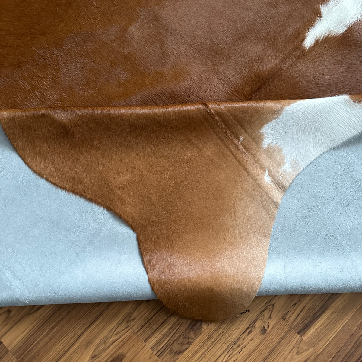 Close-up texture of Brown and White cowhide rug — Large irregular chocolate brown patches over cream base with white markings
