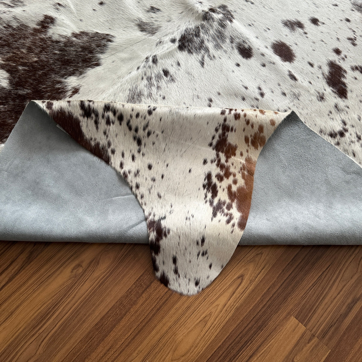 Close-up texture of Brown and White cowhide rug — Large irregular dark brown and black patches scattered over cream-white bas