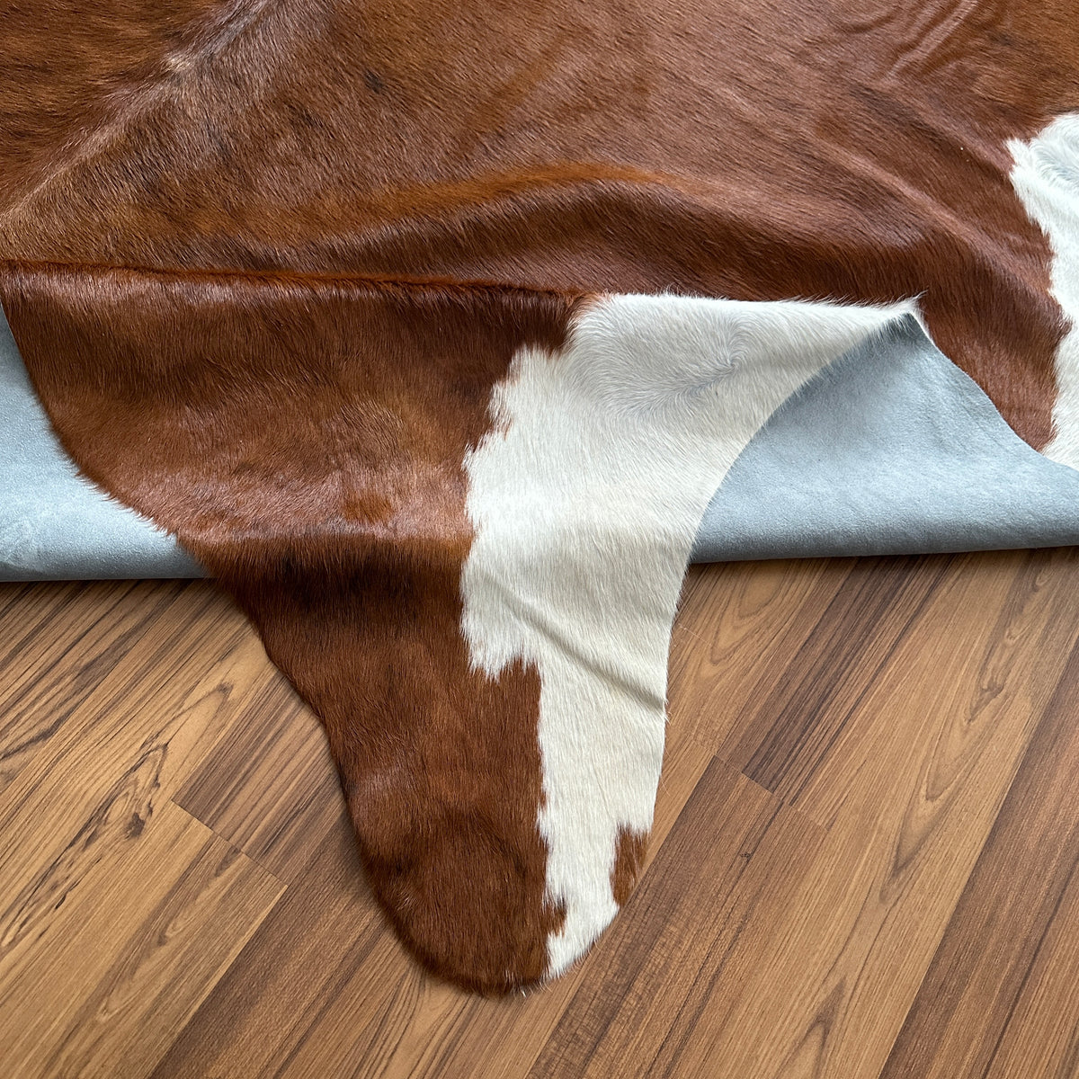 Close-up texture of Brown and White cowhide rug — Large irregular chocolate brown patches with white markings along edges and