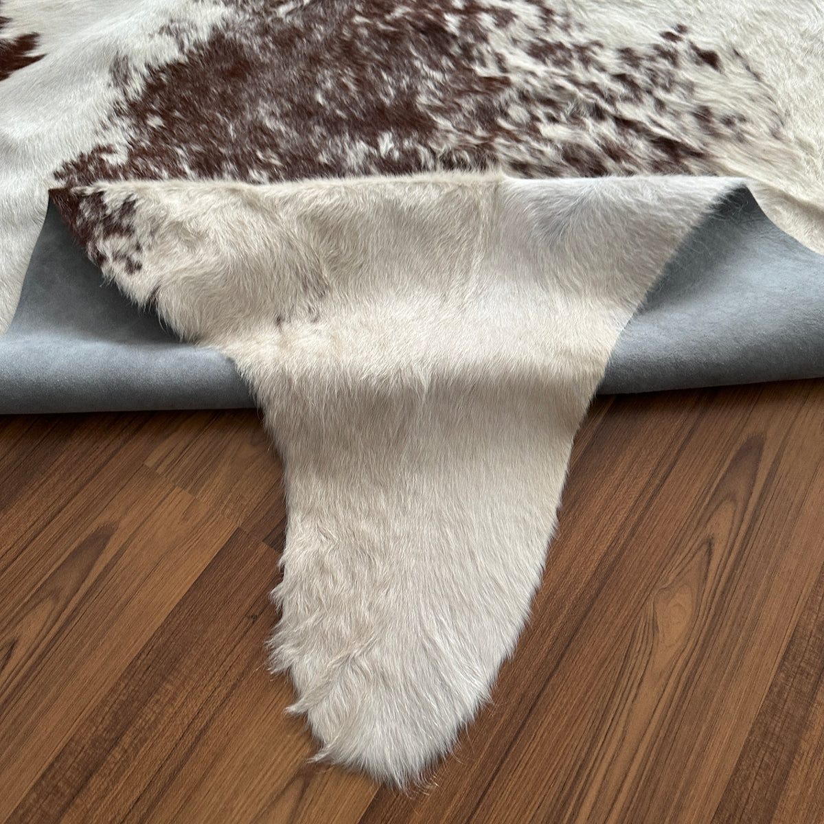 Close-up texture of Brown and White cowhide rug — Large irregular dark brown patches scattered across cream base with fine sp