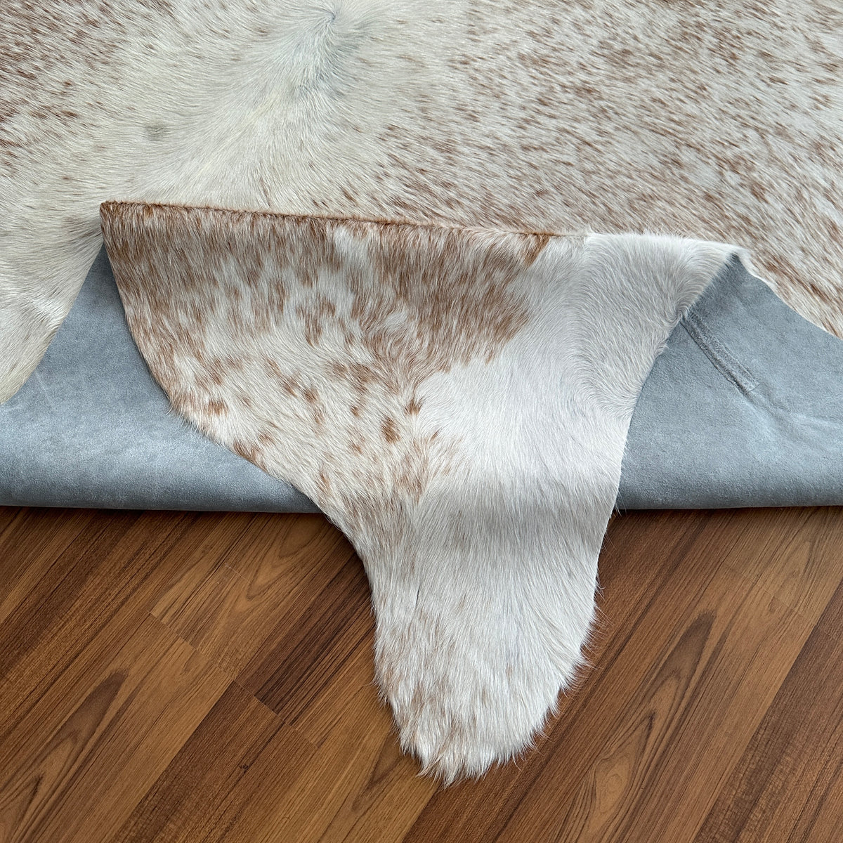 Close-up texture of Brown and White cowhide rug — Large irregular tan and brown patches over cream and white base