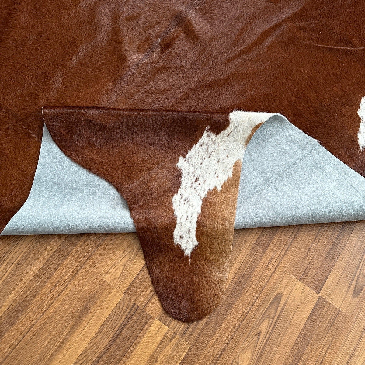 Close-up texture of Brown and White cowhide rug — Large irregular chocolate brown patches with cream and white speckled accen