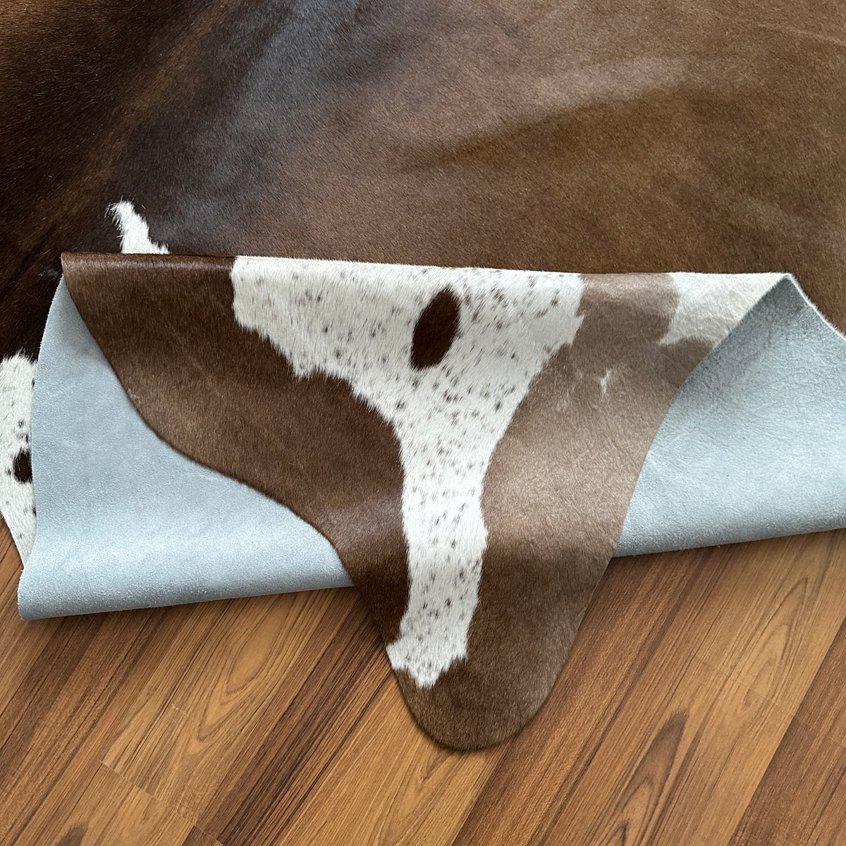 Close-up texture of Brown and White cowhide rug — Large irregular dark brown patches over white cream base with natural hide