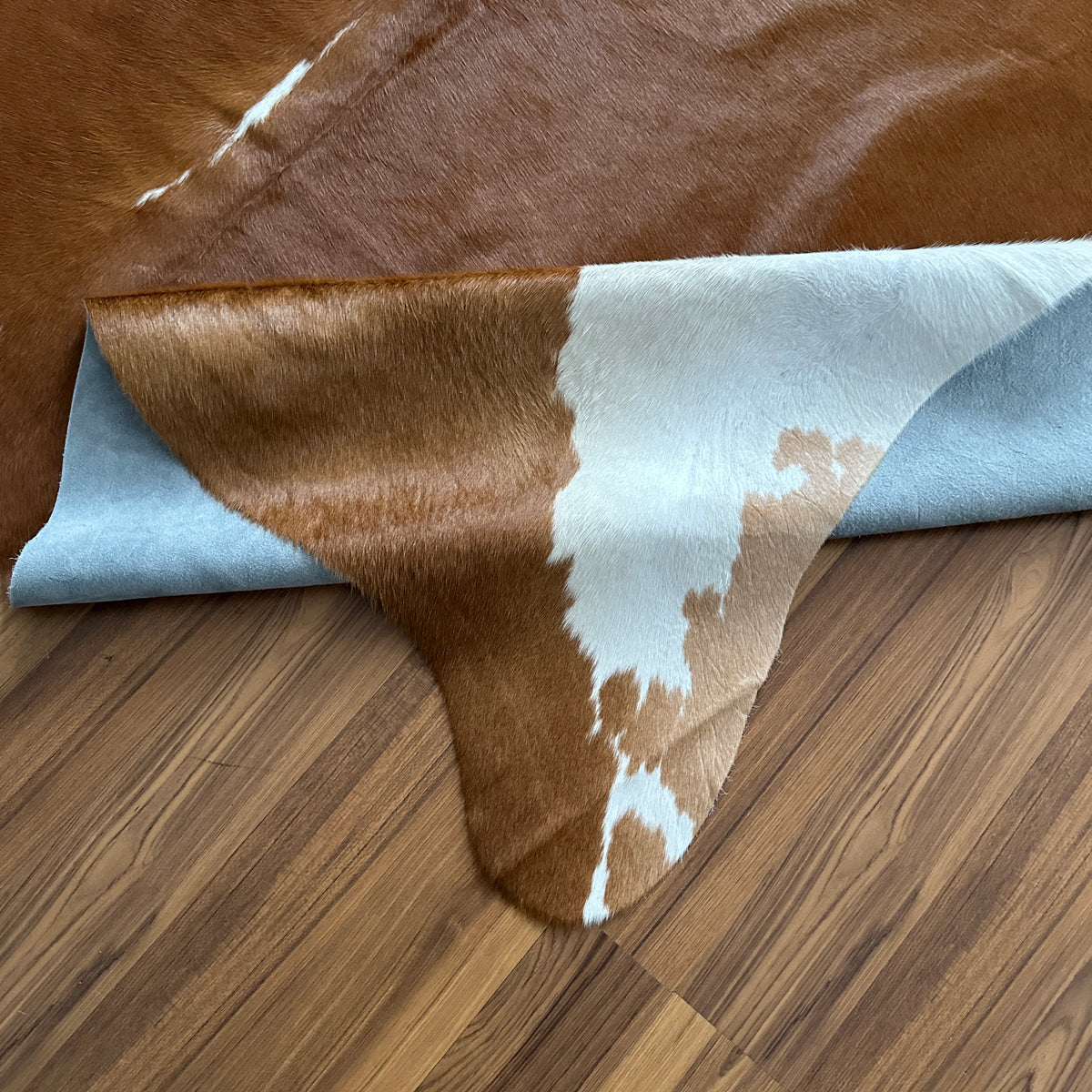 Close-up texture of Brown and White cowhide rug — Large irregular chocolate brown patches with cream and white accents on nat