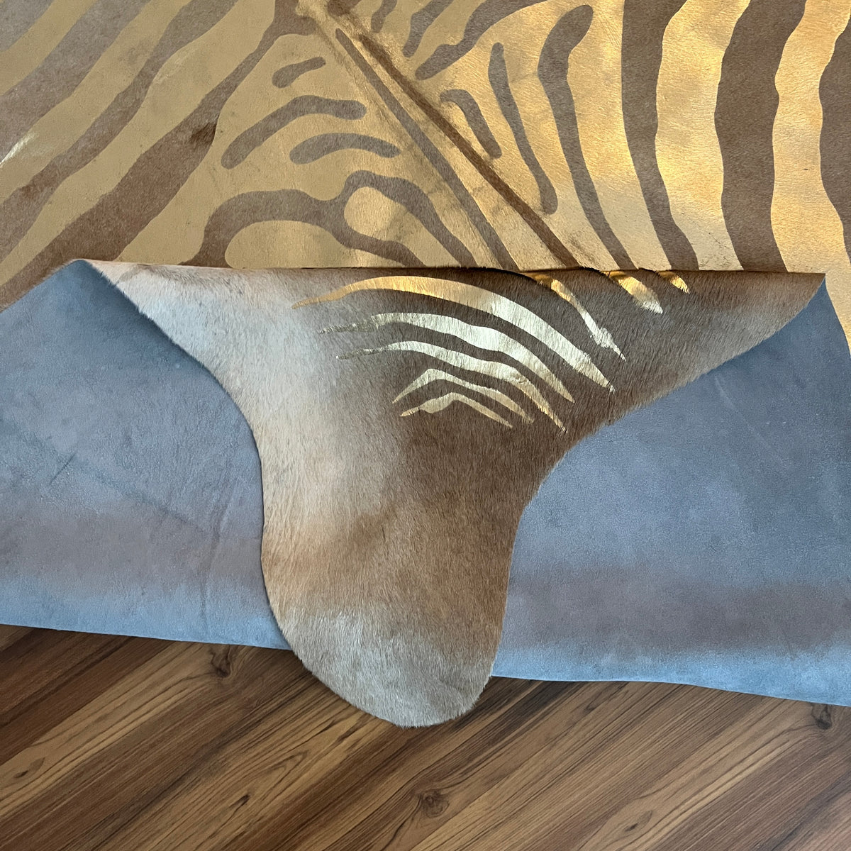 Close-up texture of Brown and White zebra print cowhide rug — Bold zebra stripes radiating from center spine, cream and tan b