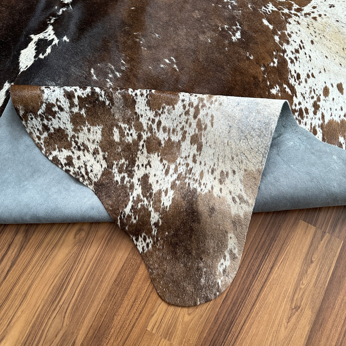 Close-up texture of Brown and White cowhide rug — Large irregular dark brown patches with cream and white speckled base