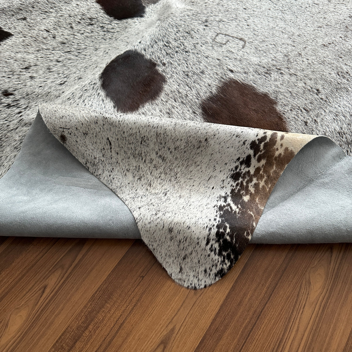 Close-up texture of Brown and White cowhide rug — Large irregular dark brown patches over cream and grey base