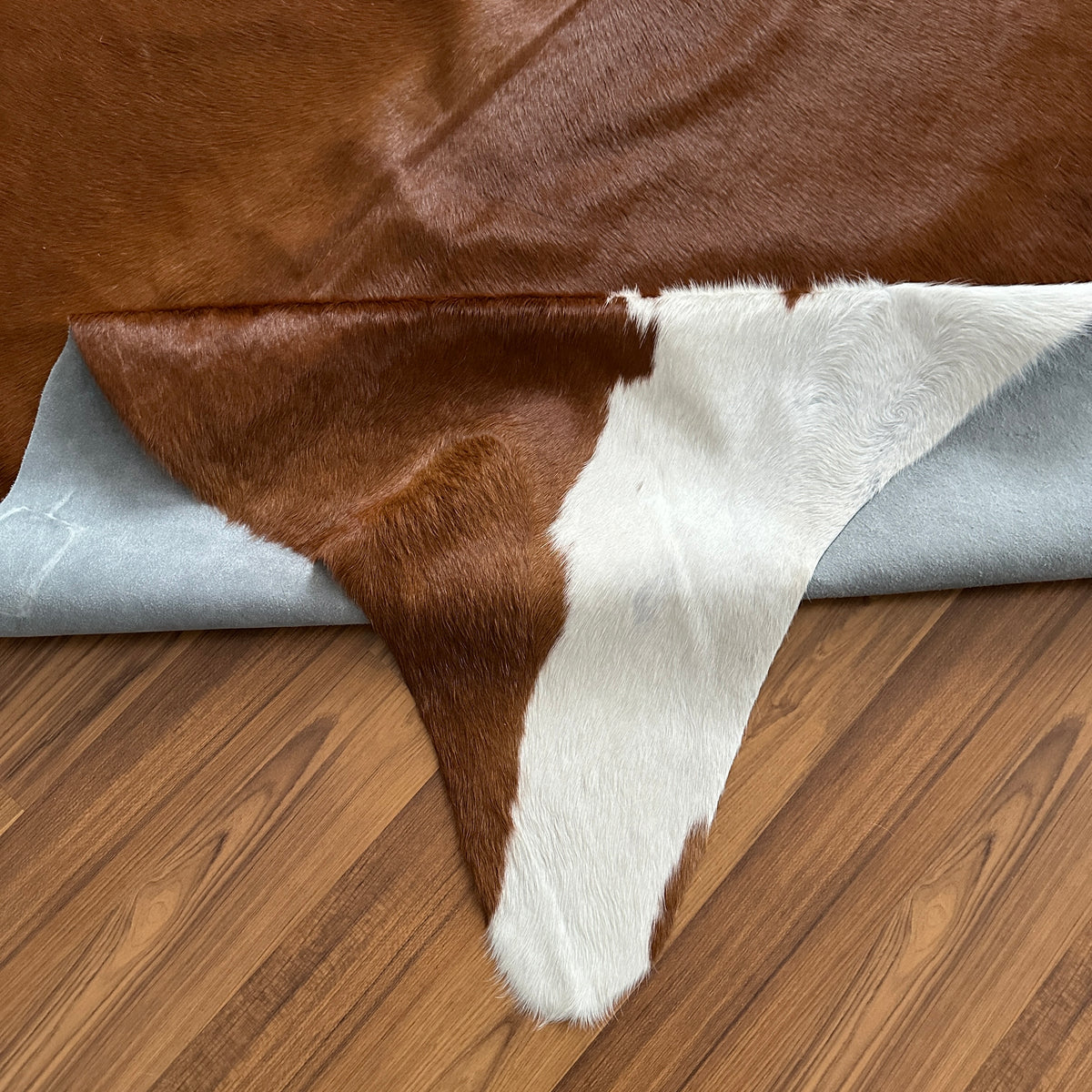 Close-up texture of Brown and White cowhide rug — Large irregular chocolate brown patches with white markings across face, ba