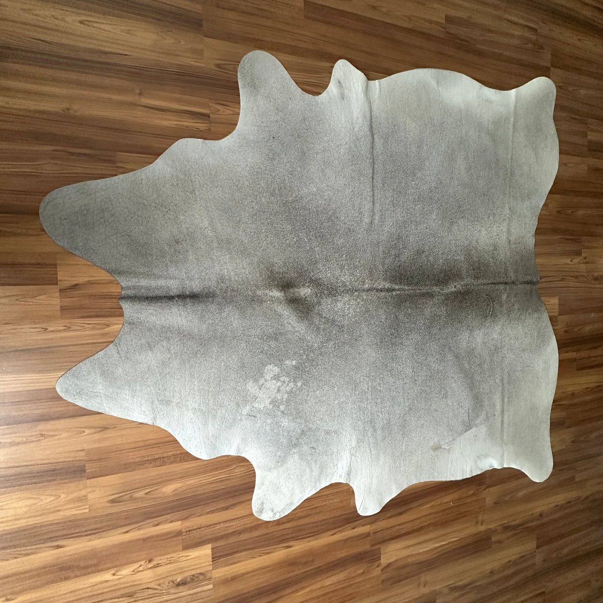 Grey cowhide rug, full overhead view — Large irregular cream and grey patches with natural mottling over a pale base