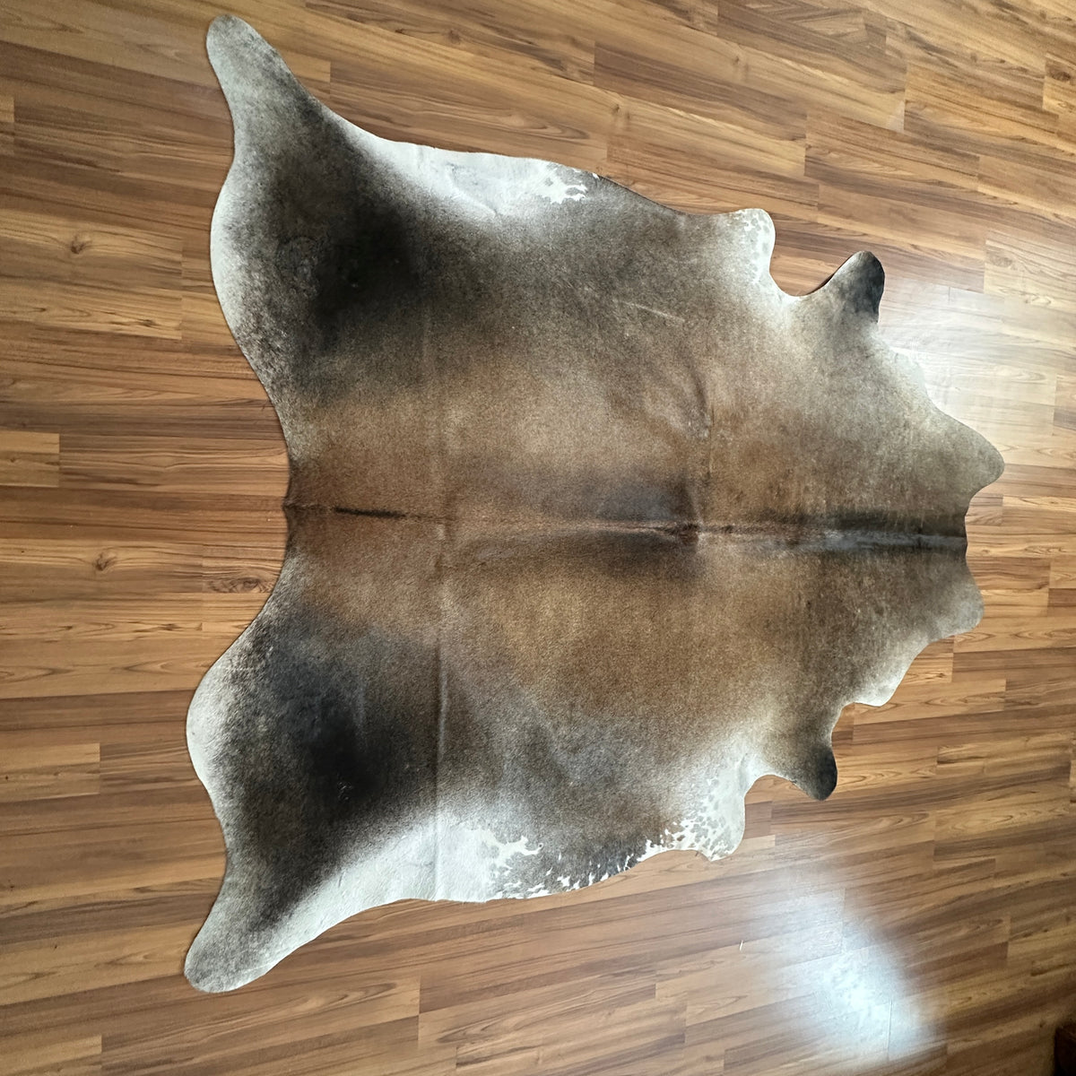 Grey cowhide rug, full overhead view — Large irregular patches of grey and white with darker undertones across natural hide