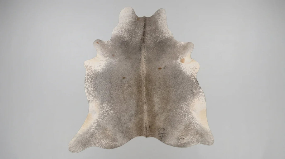 Grey cowhide rug flat lay on white background showing full hide shape