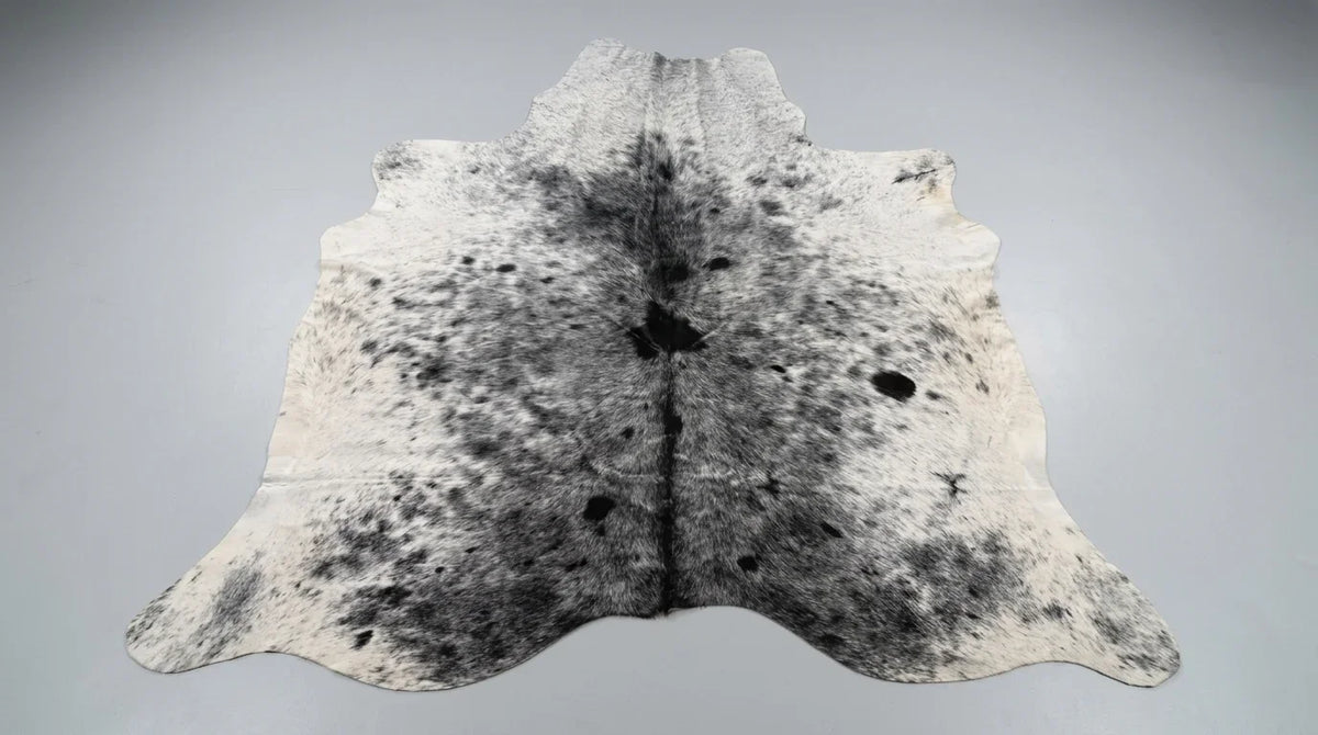 Grey cowhide rug flat lay on white background showing full hide shape