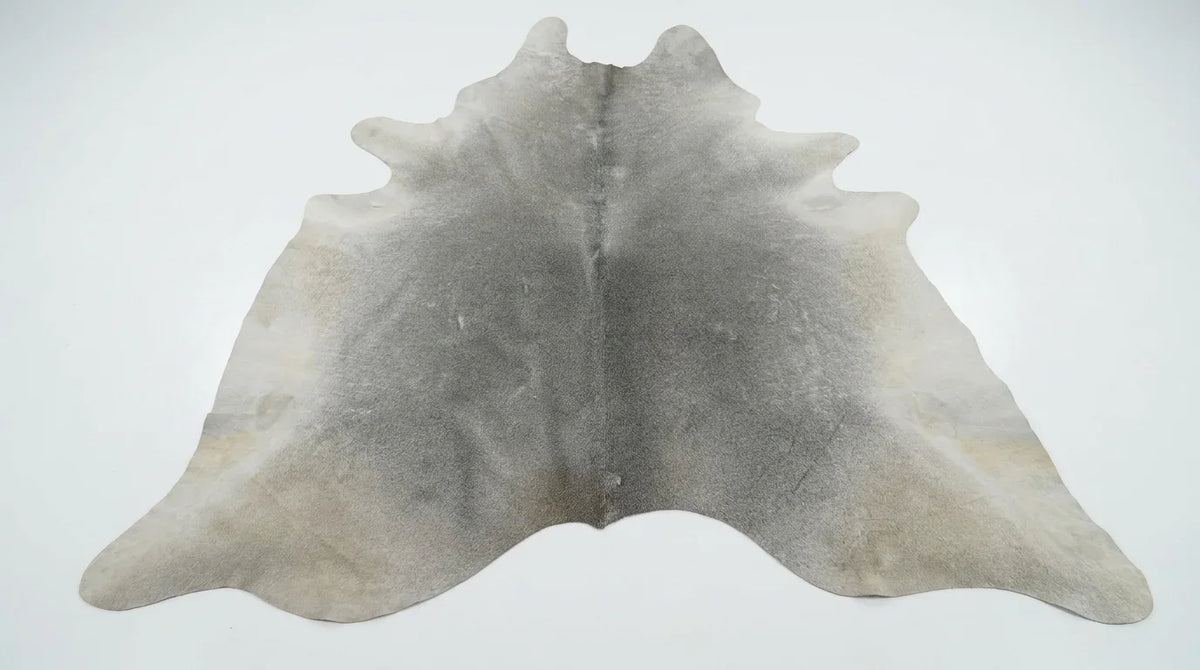 Grey cowhide rug flat lay on white background showing full hide shape