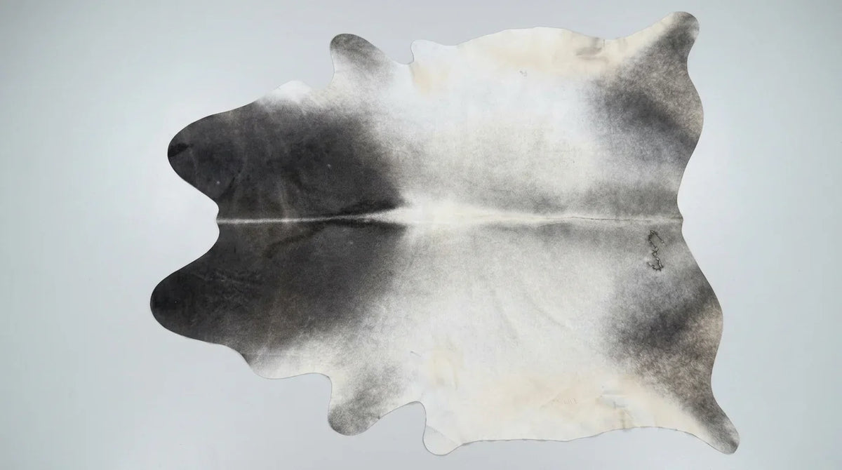 Grey cowhide rug flat lay on white background showing full hide shape